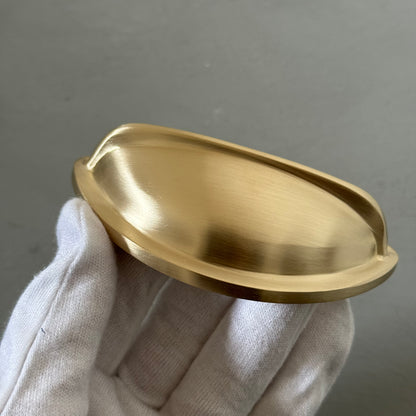 white glove hand holding one traditional brass cup pull handle