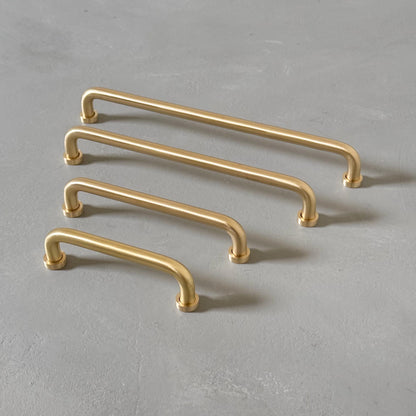 four rounded brass bar handles taken from an angle