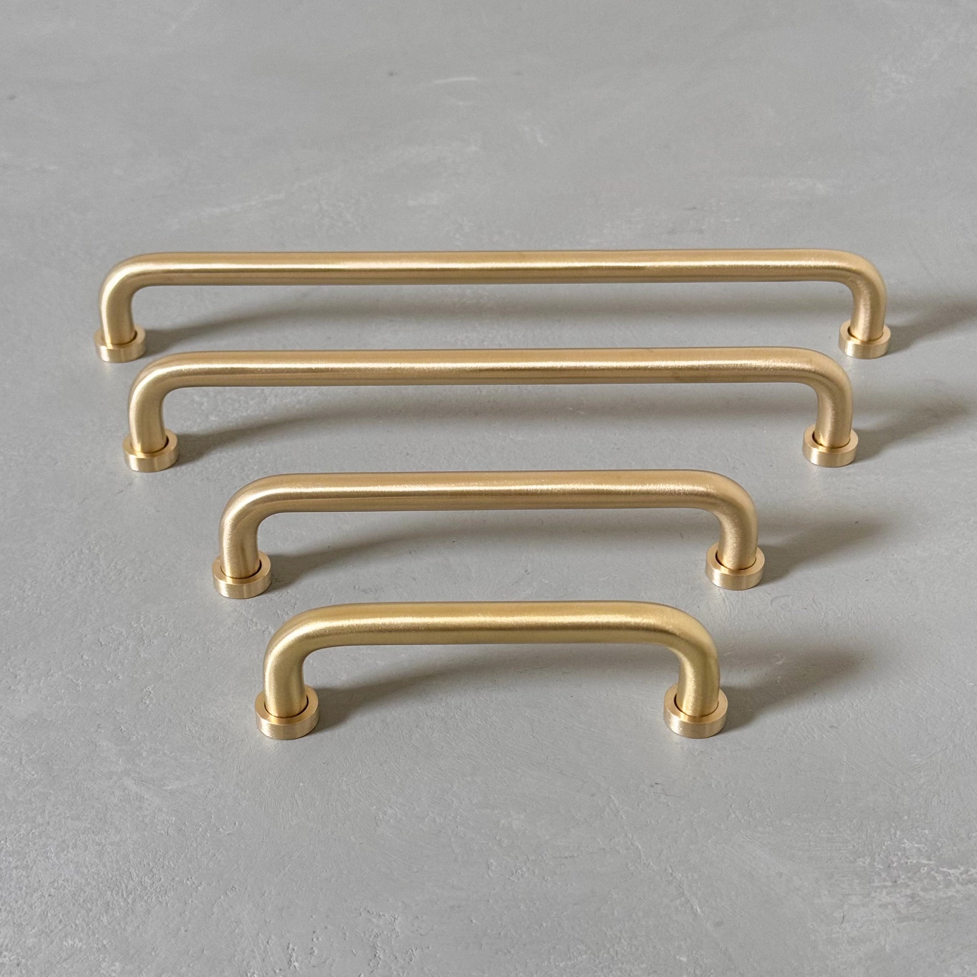 four rounded brass bar handles taken from front angle