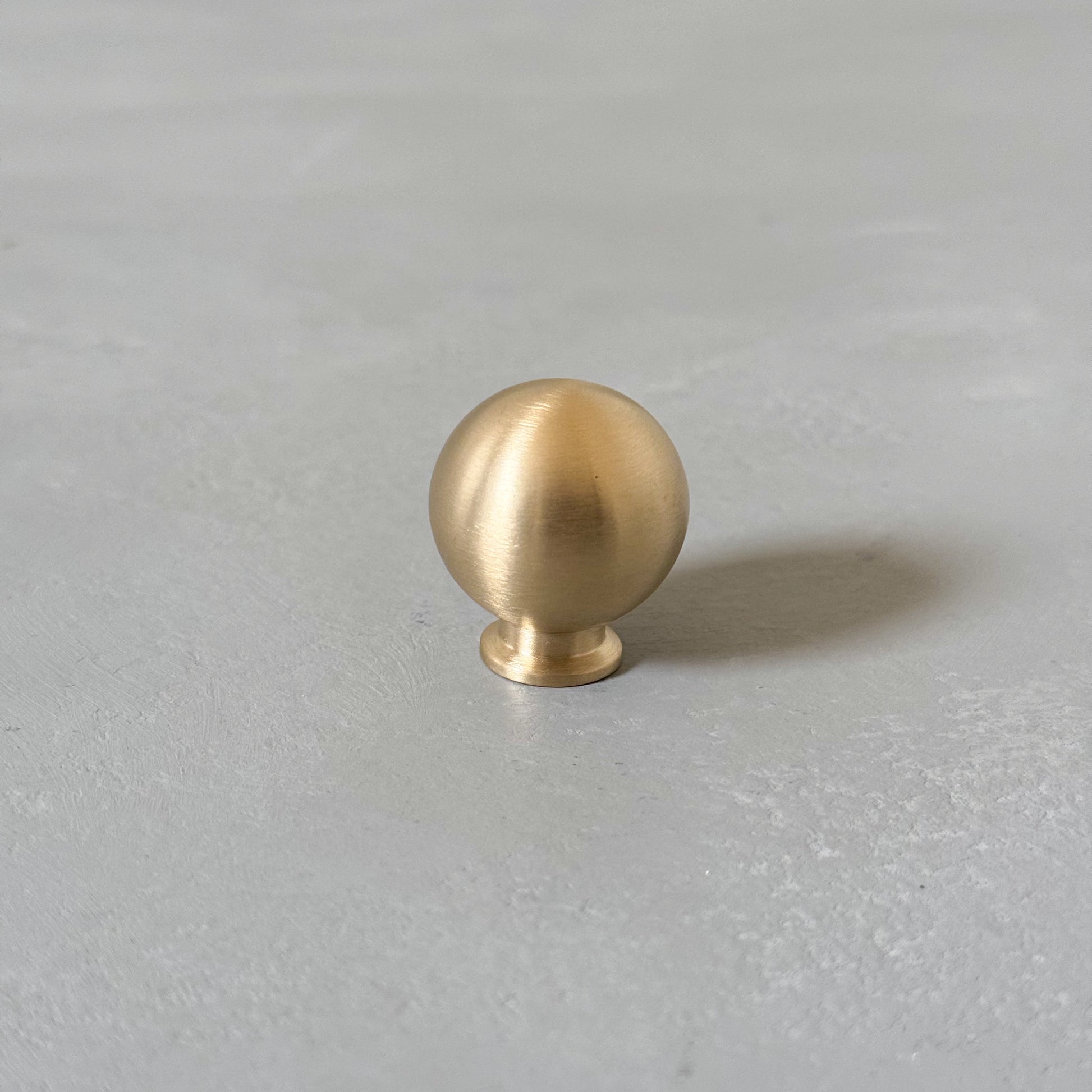 one single brass gold ball knob on grey background