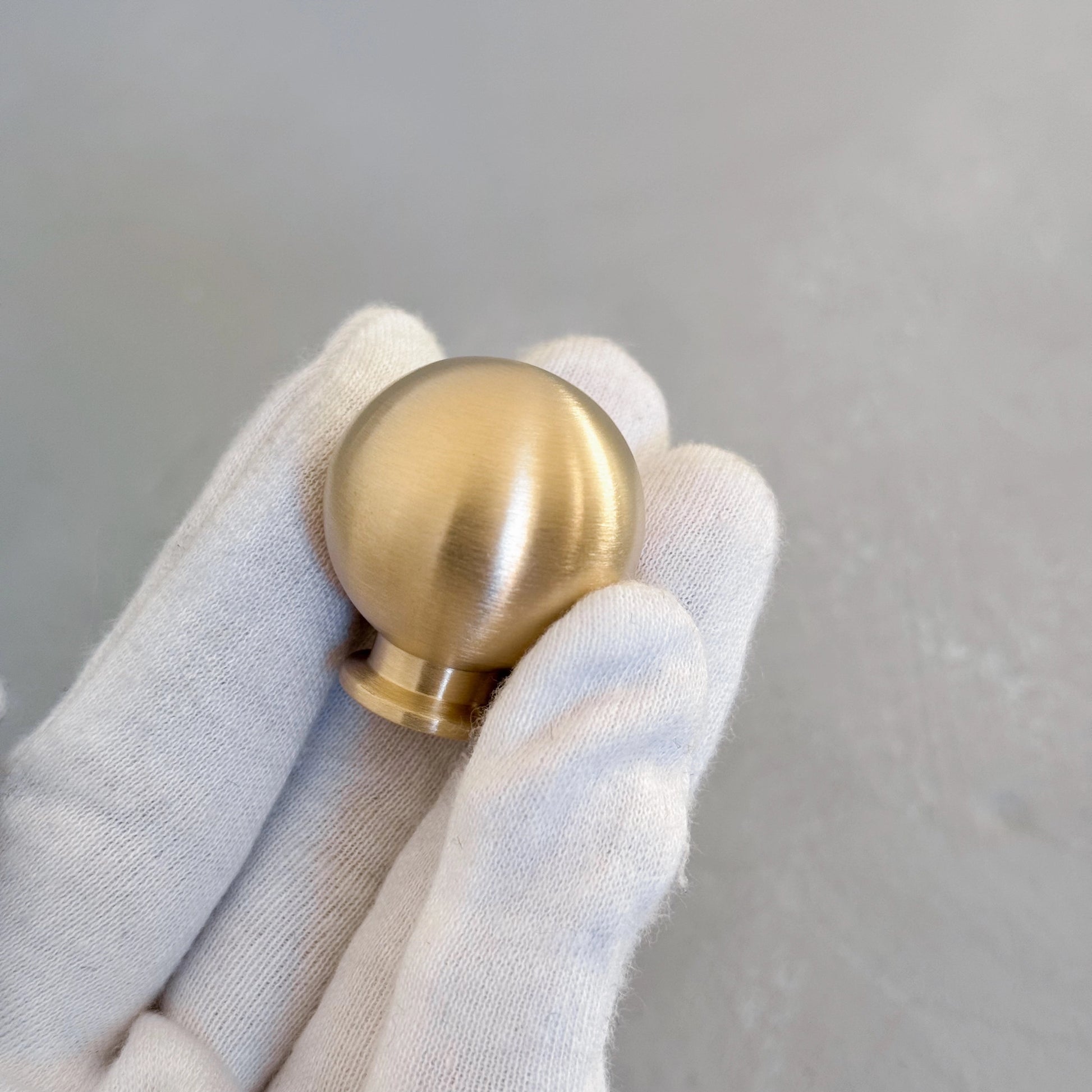 hand with white glove holding a brass ball knob