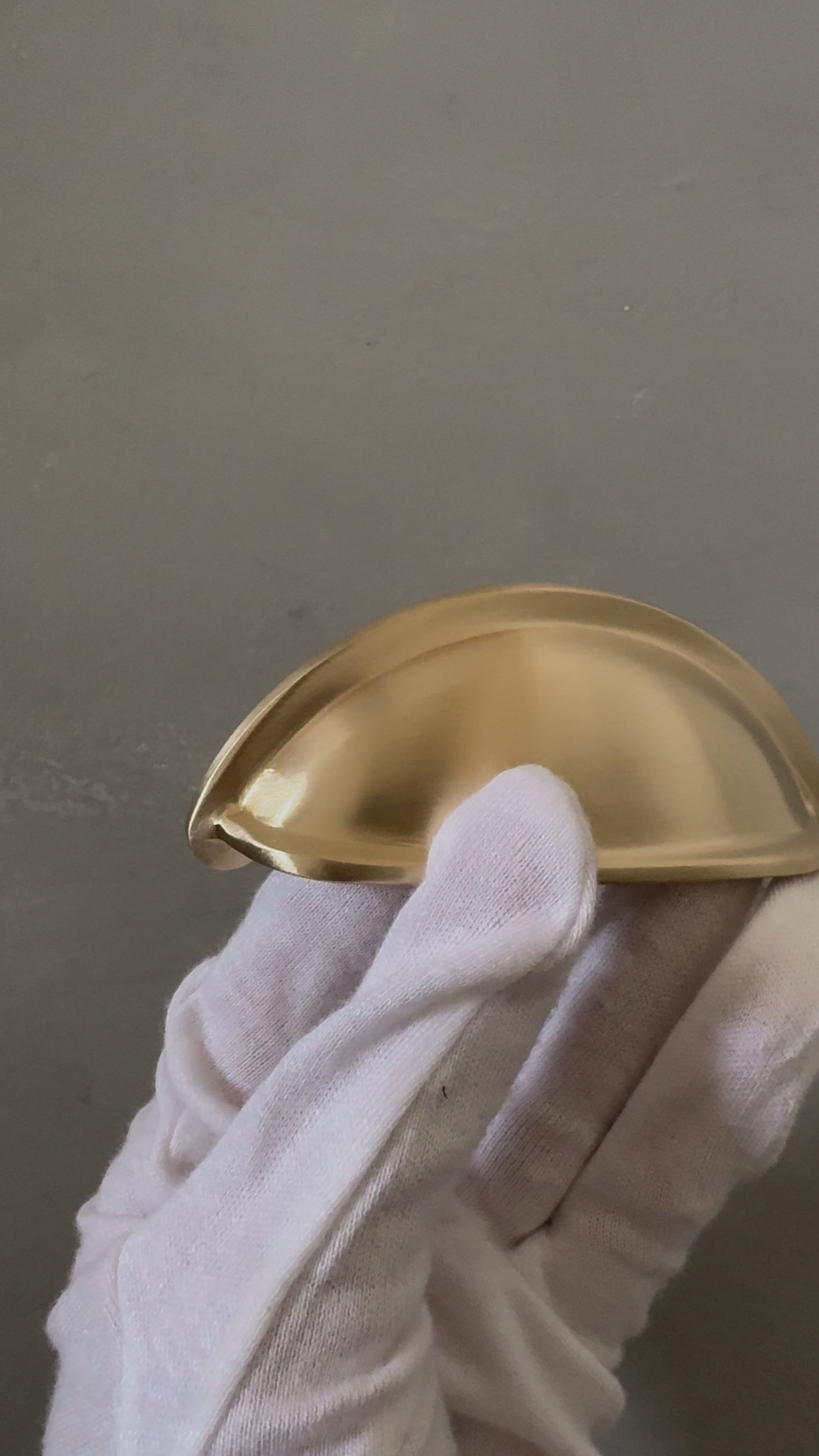 video of one traditional brass cup pull handle on white glove hand